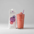 Sweetbird Mixed Berry smoothie mix carton with a glass of pink smoothie on a wooden surface.