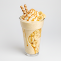 Banana milkshake with caramel sauce and whipped cream in a glass on a white background