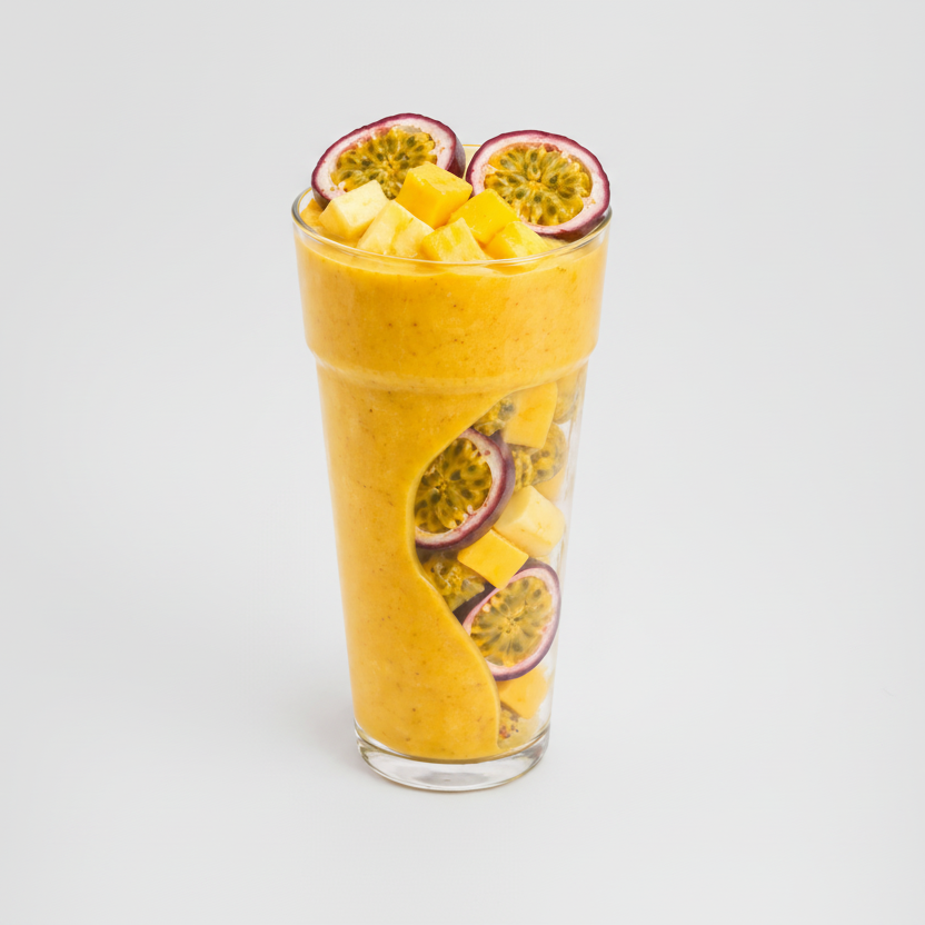 Glass of yellow smoothie with passion fruit slices on a white background